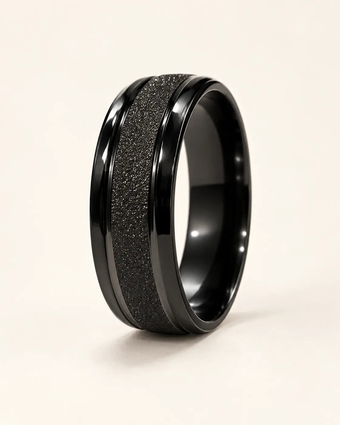 Black Eternite band ring with matte textured centre on a cream background
