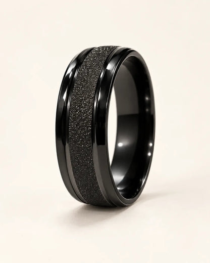 Black Eternite band ring with matte textured centre on a cream background