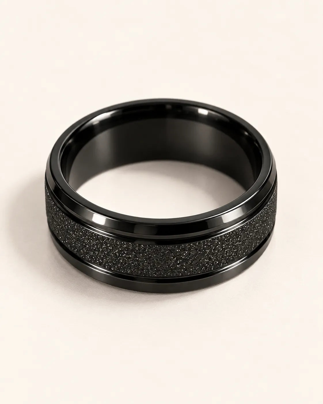 Black textured band ring lying on its side showing the glossy inner band