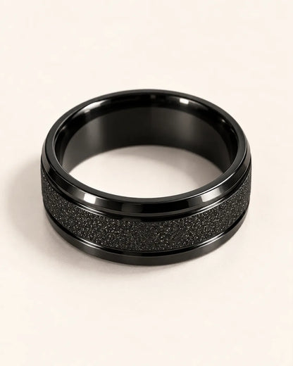 Black textured band ring lying on its side showing the glossy inner band