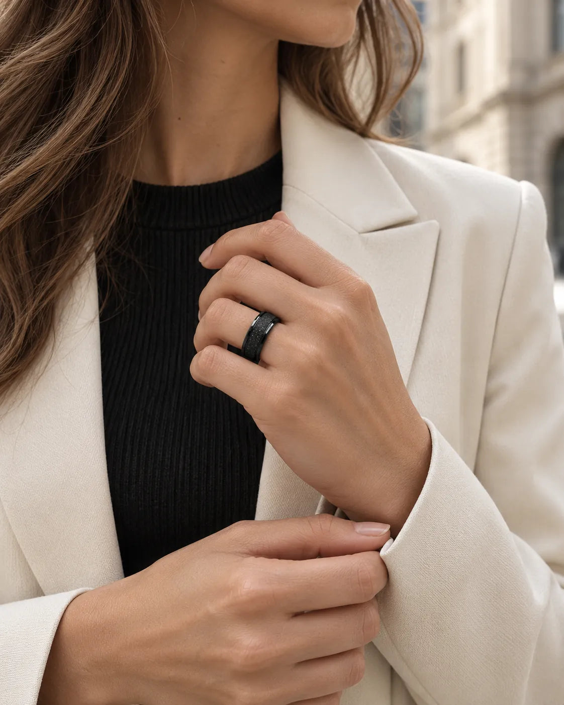Woman in a cream blazer and black top wearing the black band ring