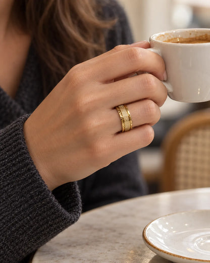 Hand wearing the gold textured band ring while holding a coffee cup