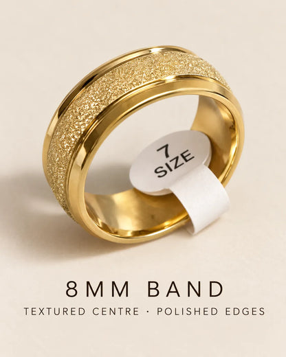 Gold 8mm band ring with a size tag and text reading textured centre, polished edges