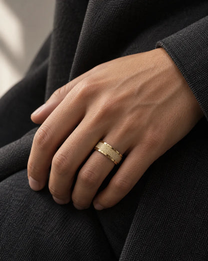 Hand wearing the gold band ring against dark clothing