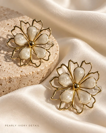 White flower statement studs resting on satin and a stone block
