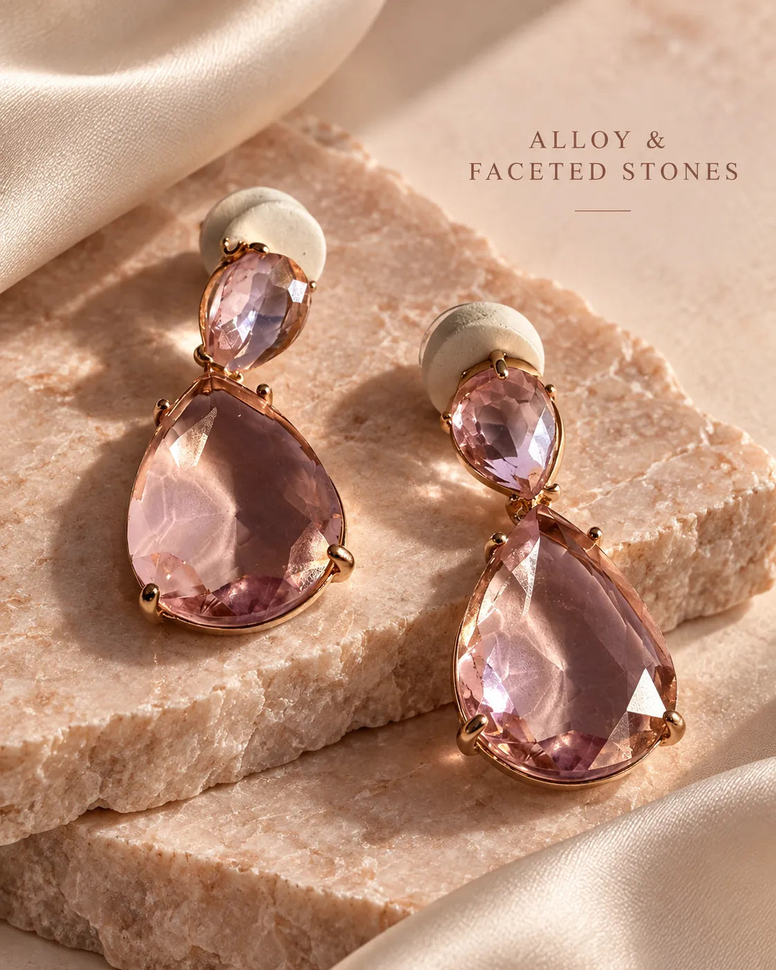 Pink crystal teardrop earrings resting on a pink stone block