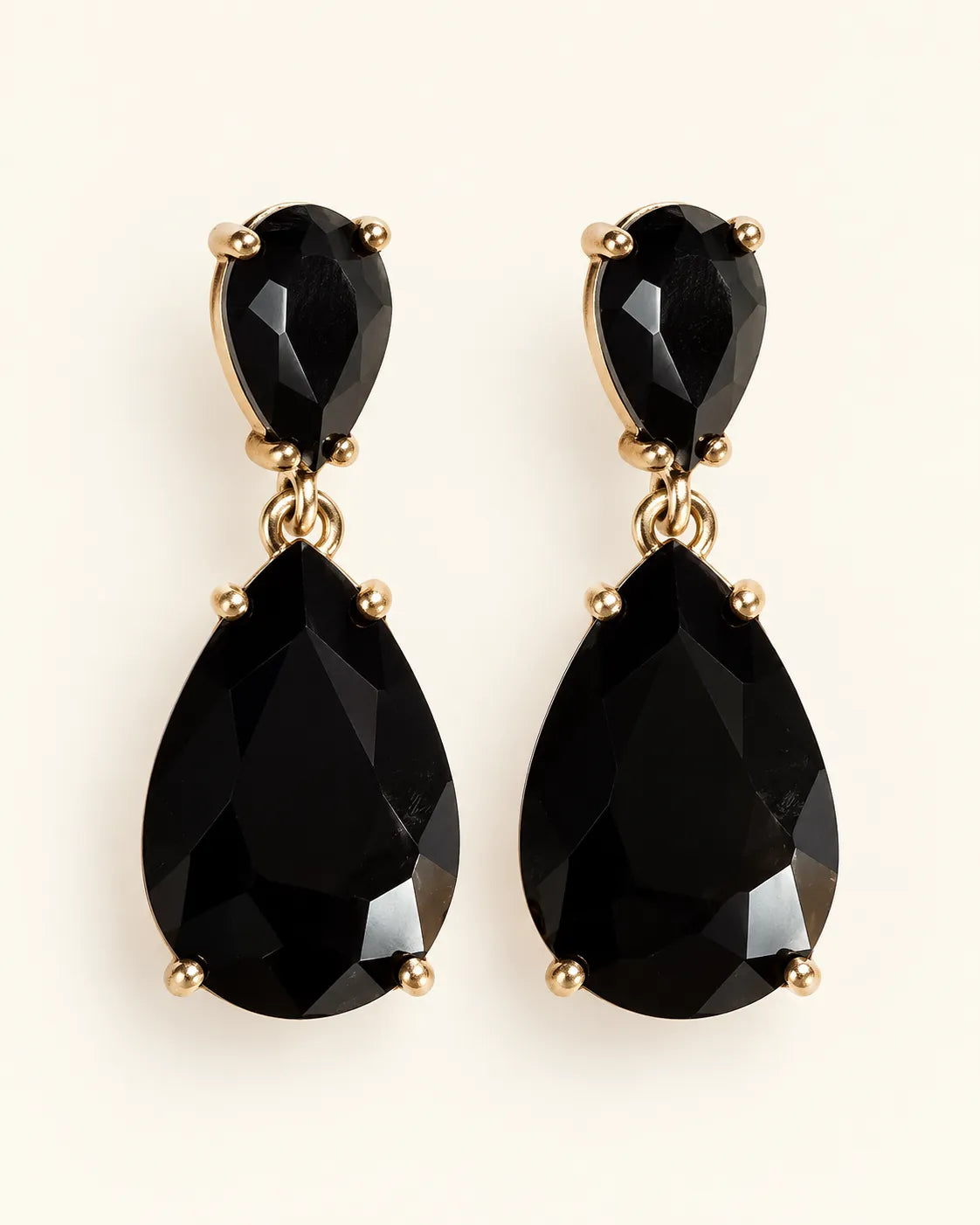 Black Elara two-stone teardrop earrings on a cream background