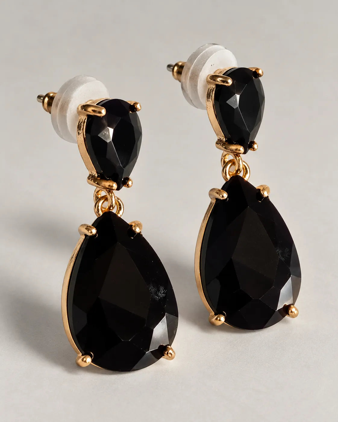 Pair of black crystal teardrop earrings with push-backs on a grey surface