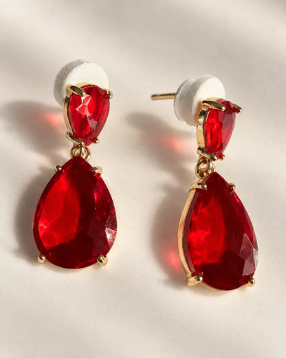 Pair of red crystal teardrop earrings with push-backs on a light surface