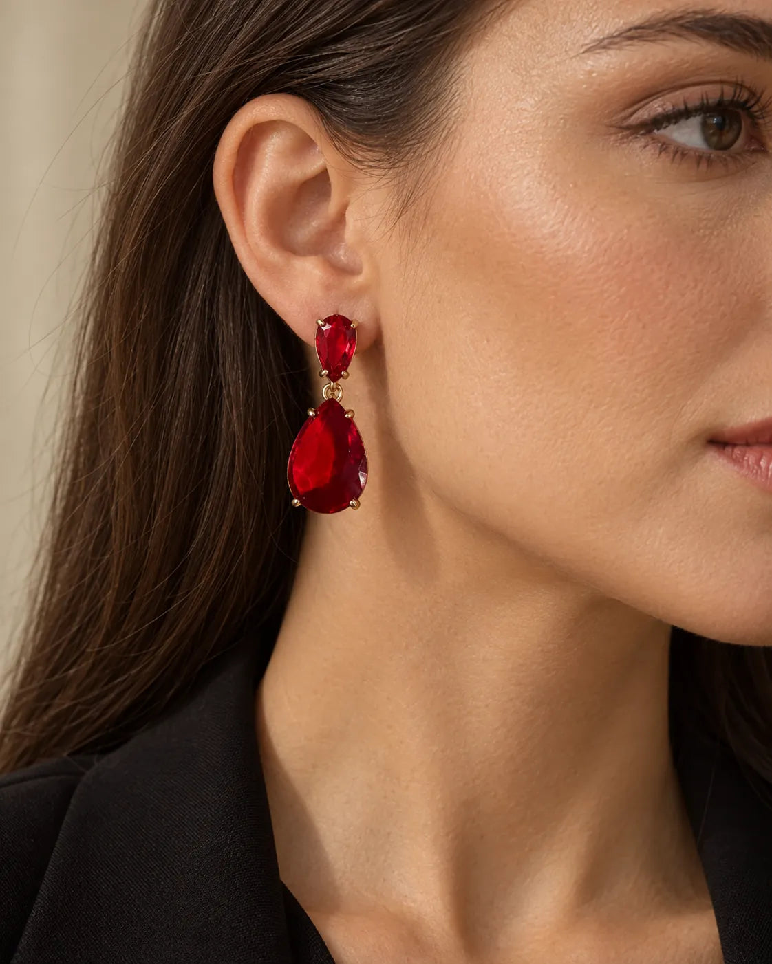 Close-up of a model's ear wearing the red crystal teardrop earring