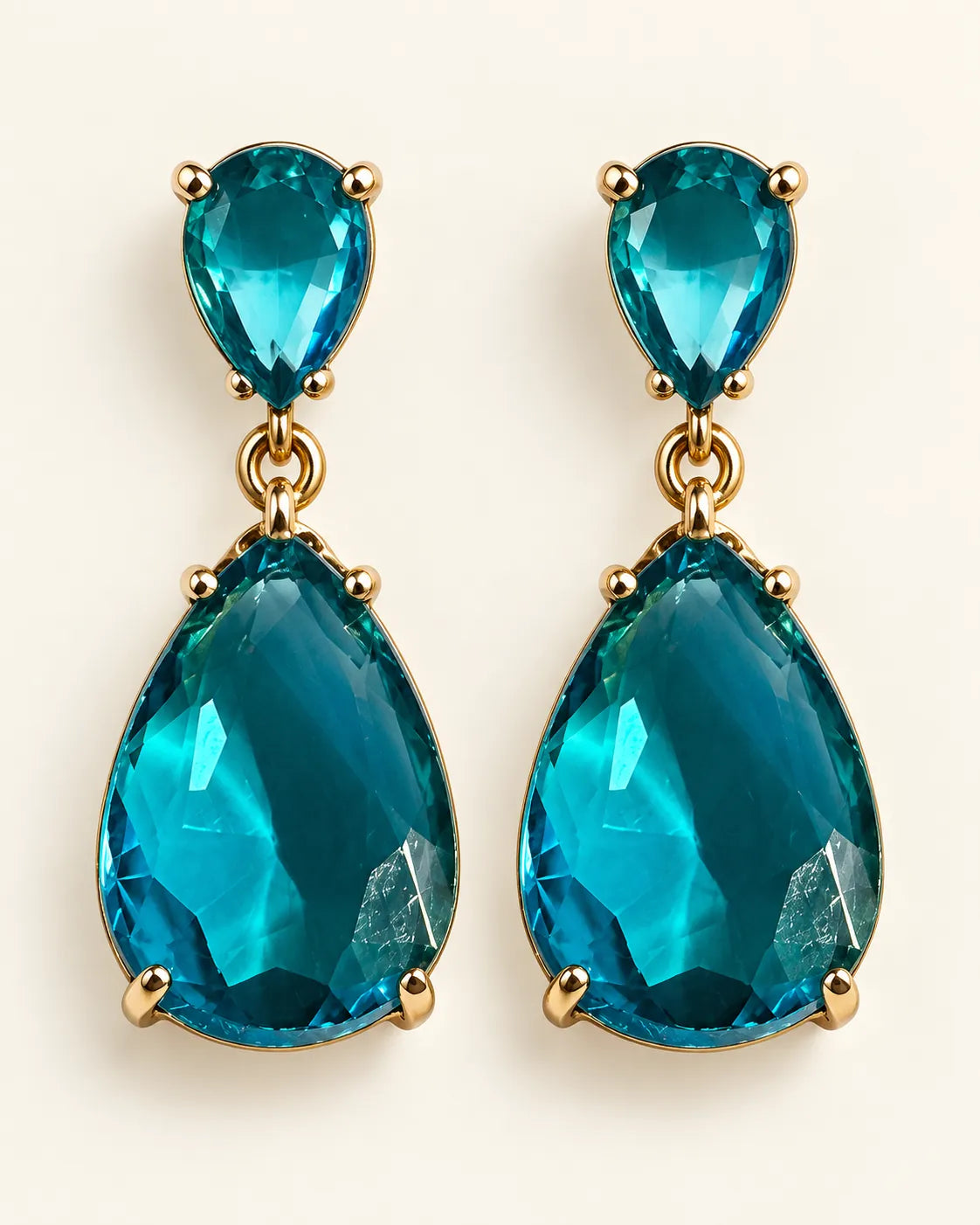 Blue Elara two-stone teardrop earrings on a cream background