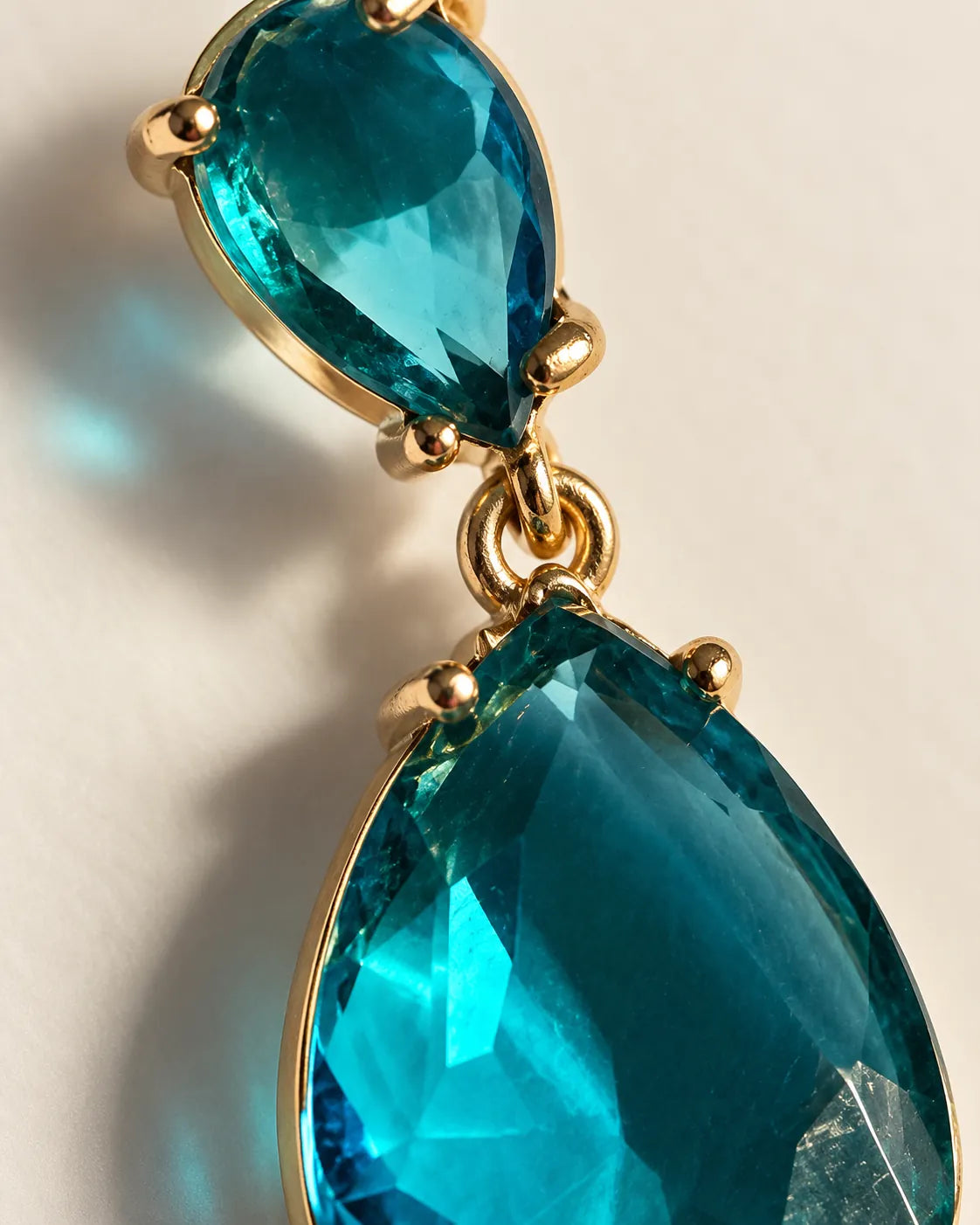 Close-up of the teal-blue faceted crystals and gold-tone claws