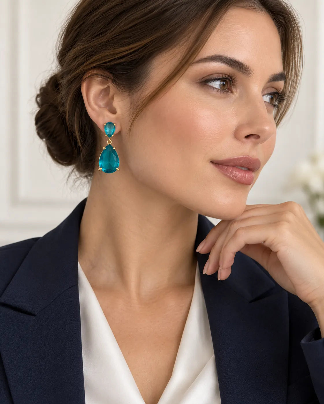 Model in a navy blazer wearing the blue crystal teardrop earrings