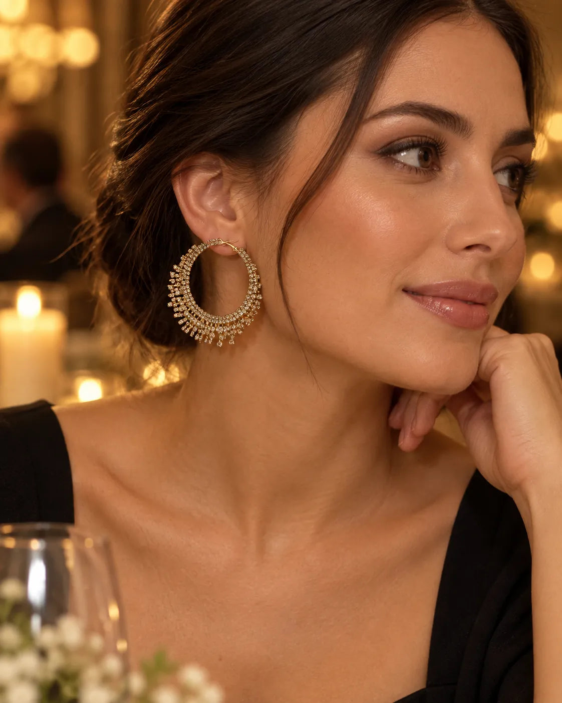 Model in a black top at an evening venue wearing the gold fringe hoops