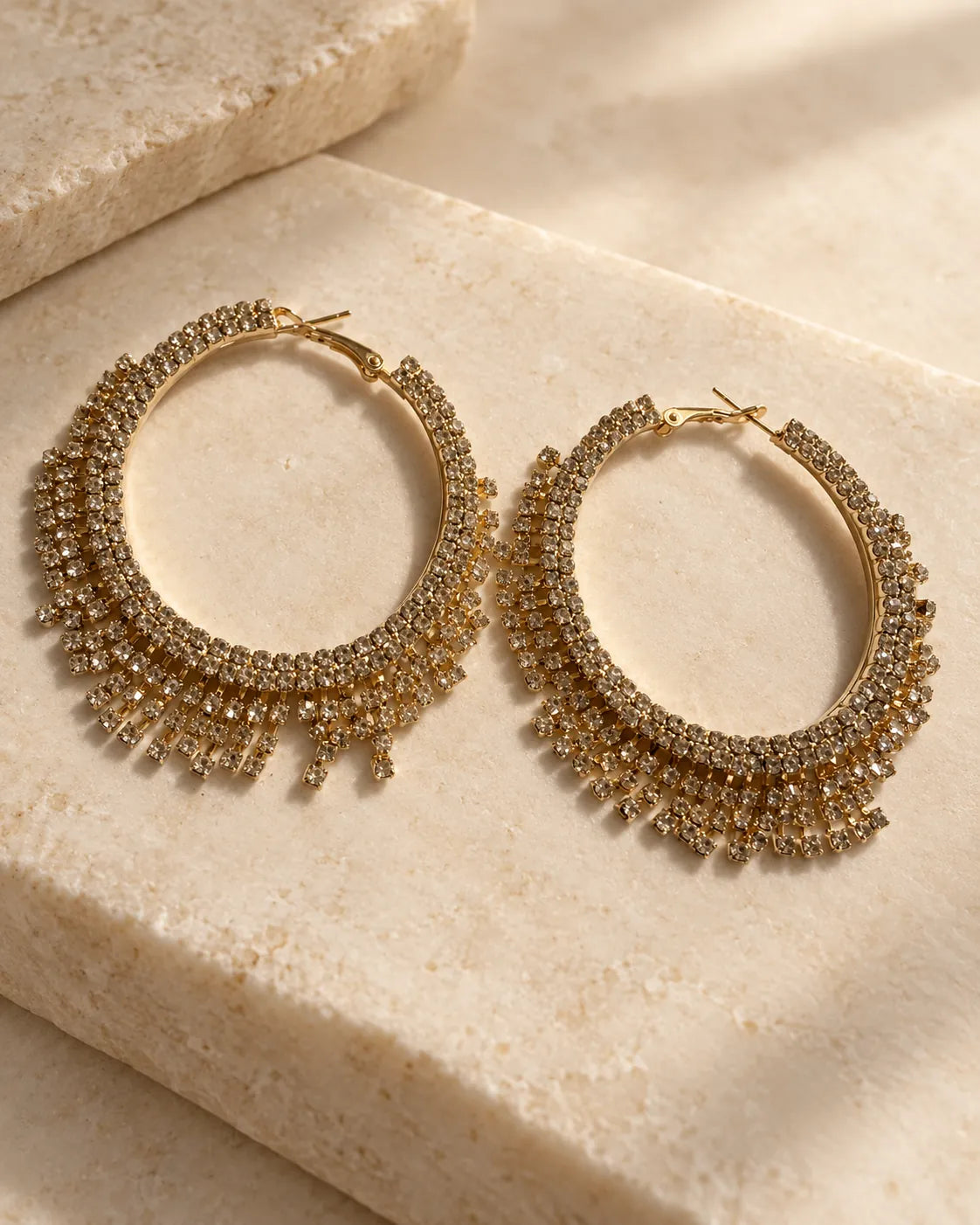 Gold crystal fringe hoops resting on a stone block