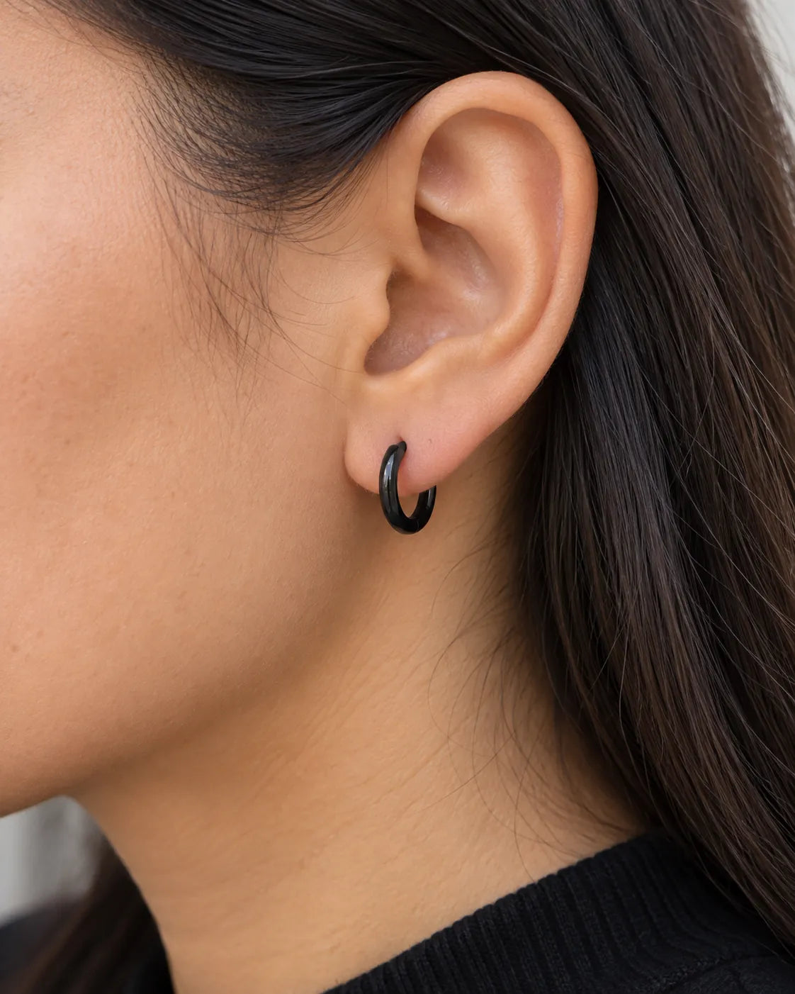Close-up of a black huggie hoop earring worn on the lobe