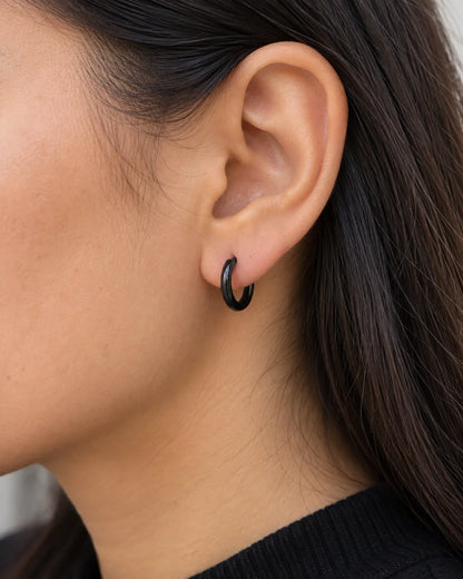 Close-up of a black huggie hoop earring worn on the lobe