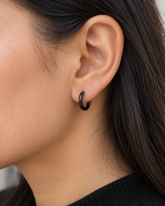 Close-up of a black huggie hoop earring worn on the lobe