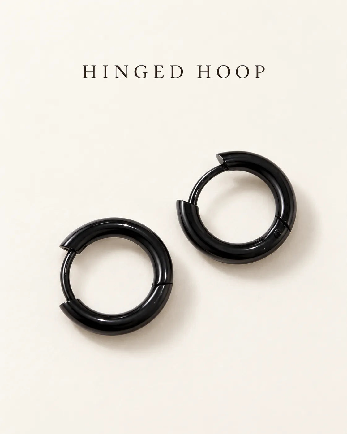 Black hinged huggie hoops on a cream card with Hinged Hoop text