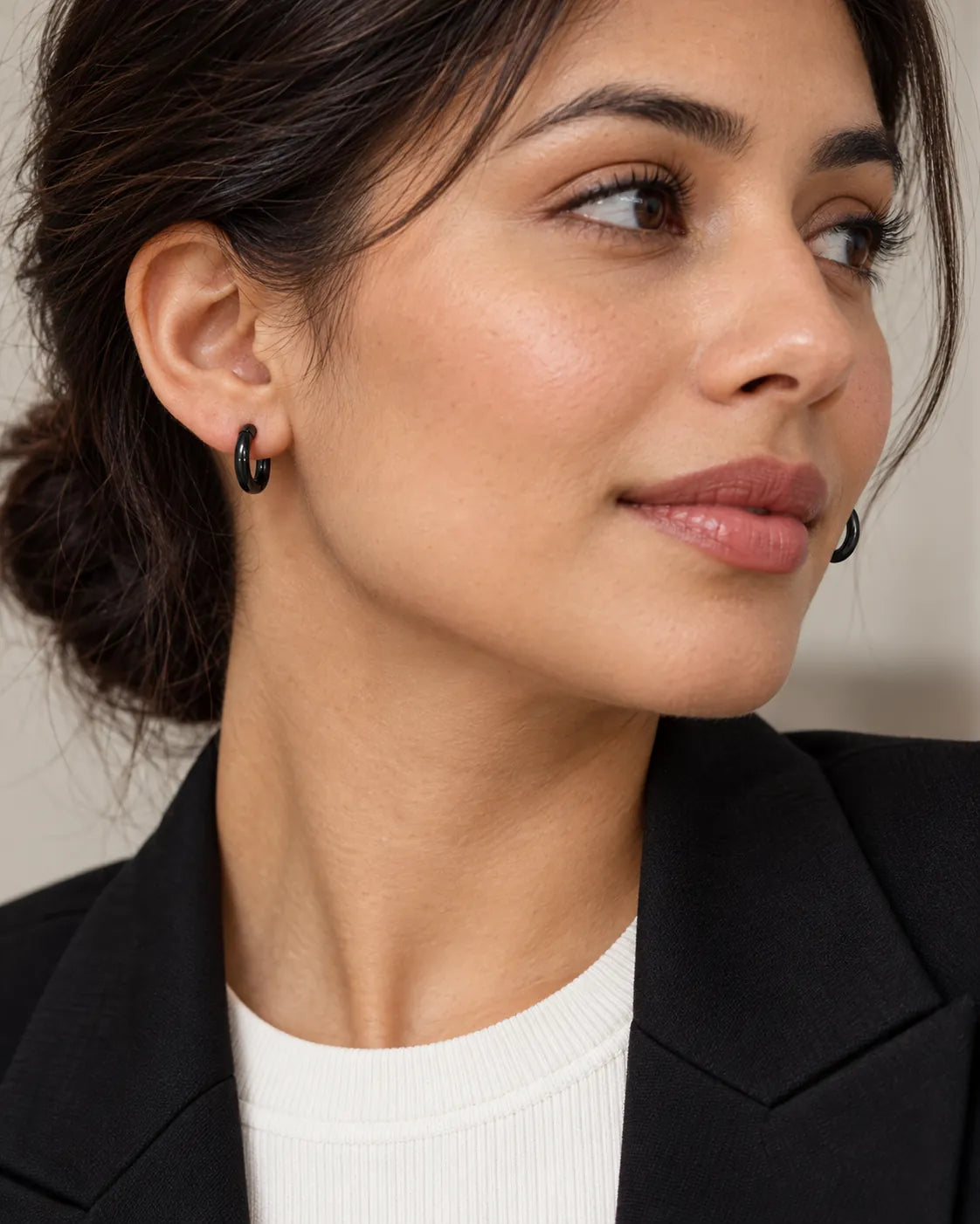 Model in a black blazer wearing black huggie hoop earrings