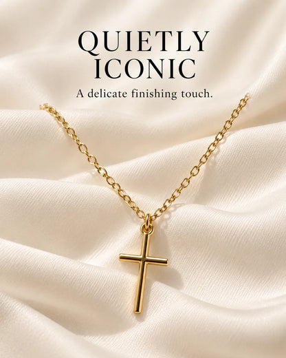 Gold cross necklace on white satin with Quietly Iconic text