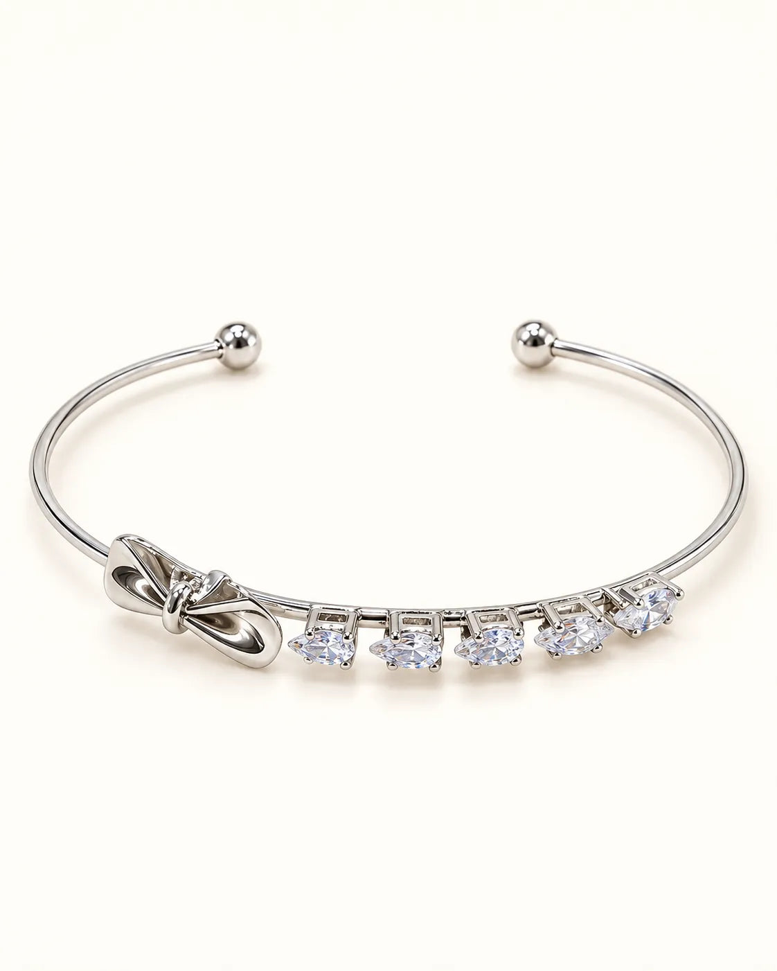 Silver open cuff bangle with a row of square zircon and a bow