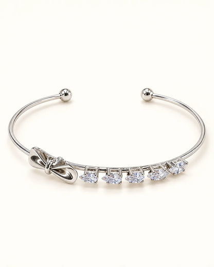 Silver open cuff bangle with a row of square zircon and a bow