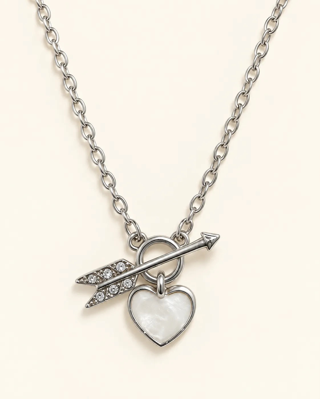 Silver-tone Amélie heart and arrow toggle necklace on a cream background