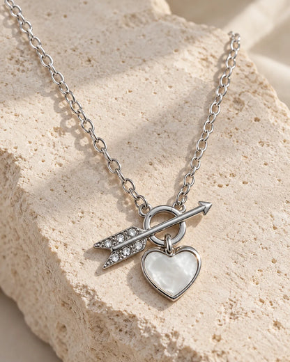 Silver toggle heart necklace draped over a textured stone block