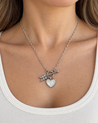 Model in a white scoop-neck top wearing the silver toggle heart necklace