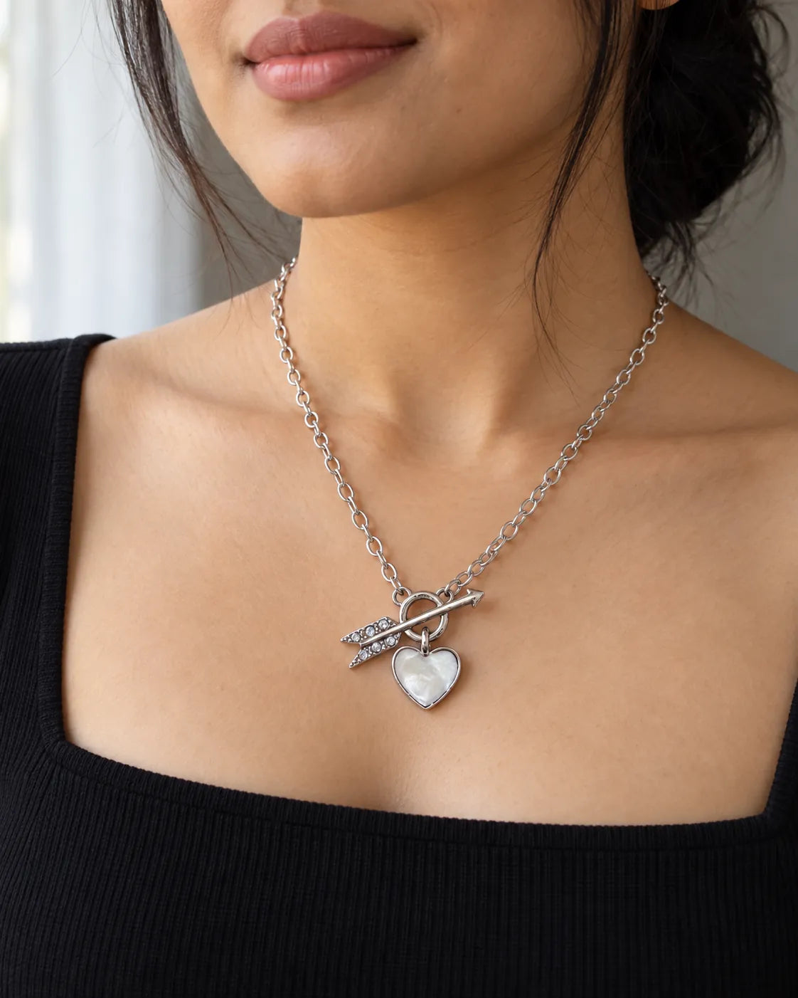 Model in a black square-neck top wearing the silver Amélie toggle necklace