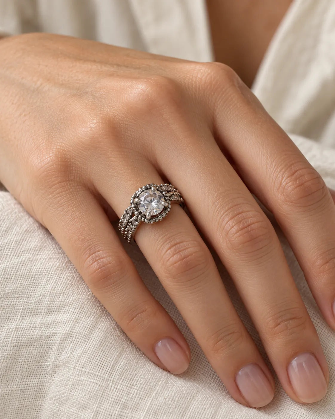 Hand resting on linen wearing the silver halo cubic zirconia ring