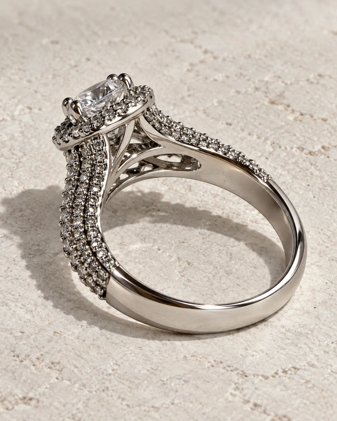 Silver split-shank halo ring on a textured cream surface