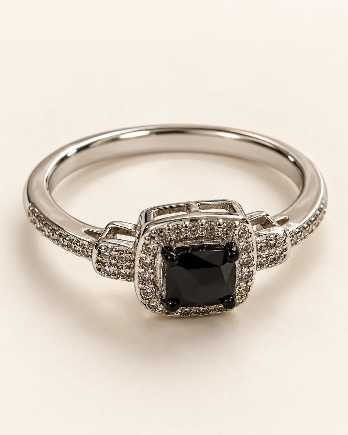 Silver halo ring with square black cubic zirconia centre on a cream background