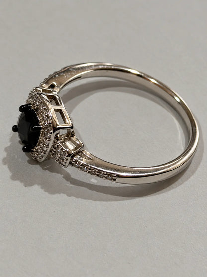 Angled view of the black and white cubic zirconia halo ring on grey