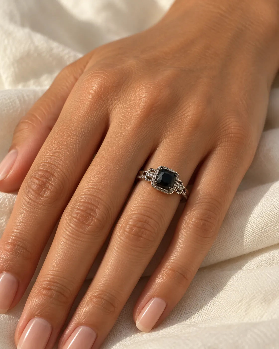 Hand on linen wearing the black and white halo ring
