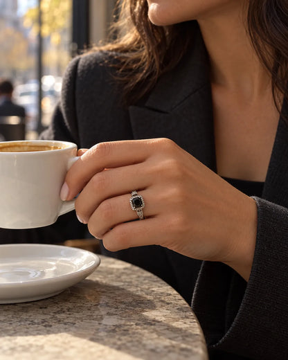Hand holding a coffee cup at a cafe wearing the black stone ring
