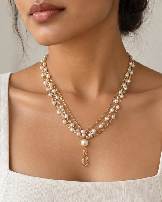 Model in a white square-neck top wearing the gold pearl cascade necklace