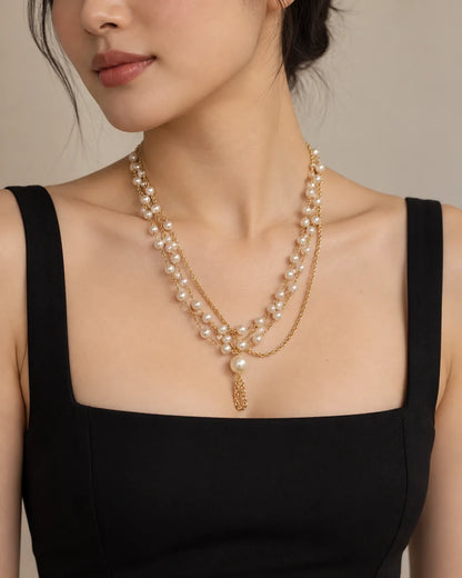 Model in a black square-neck tank wearing the gold pearl cascade necklace