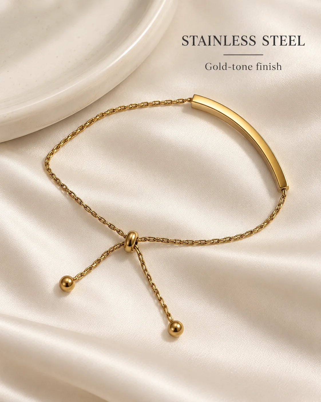 Stainless steel Aria bracelet with gold-tone finish on a cream dish