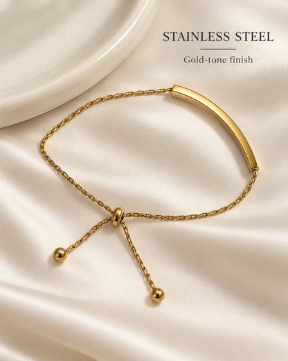 Stainless steel Aria bracelet with gold-tone finish on a cream dish