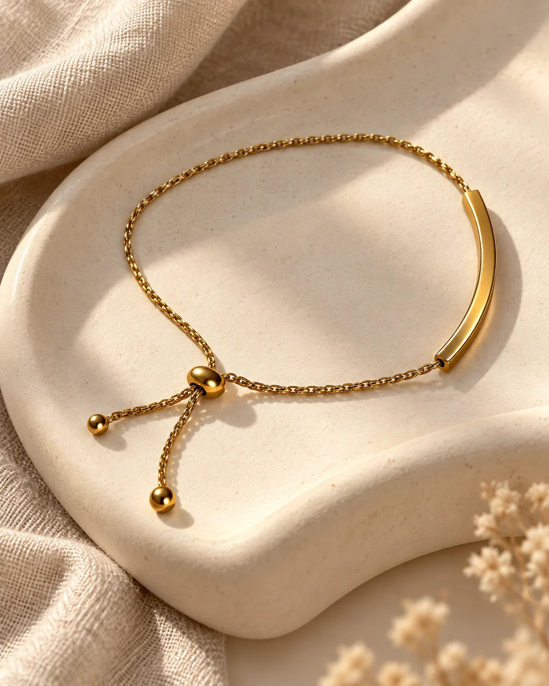 Gold curved bar slider bracelet on an ivory dish showing the sliding bead closure