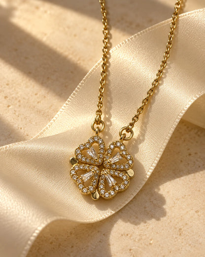 Amora four-heart clover pendant resting on cream satin ribbon in warm golden light