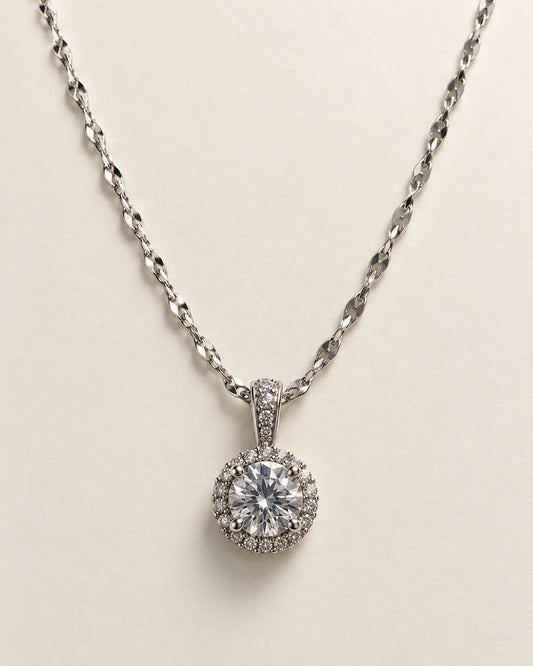 Luna silver round halo pendant with a clear centre stone on a cream background
