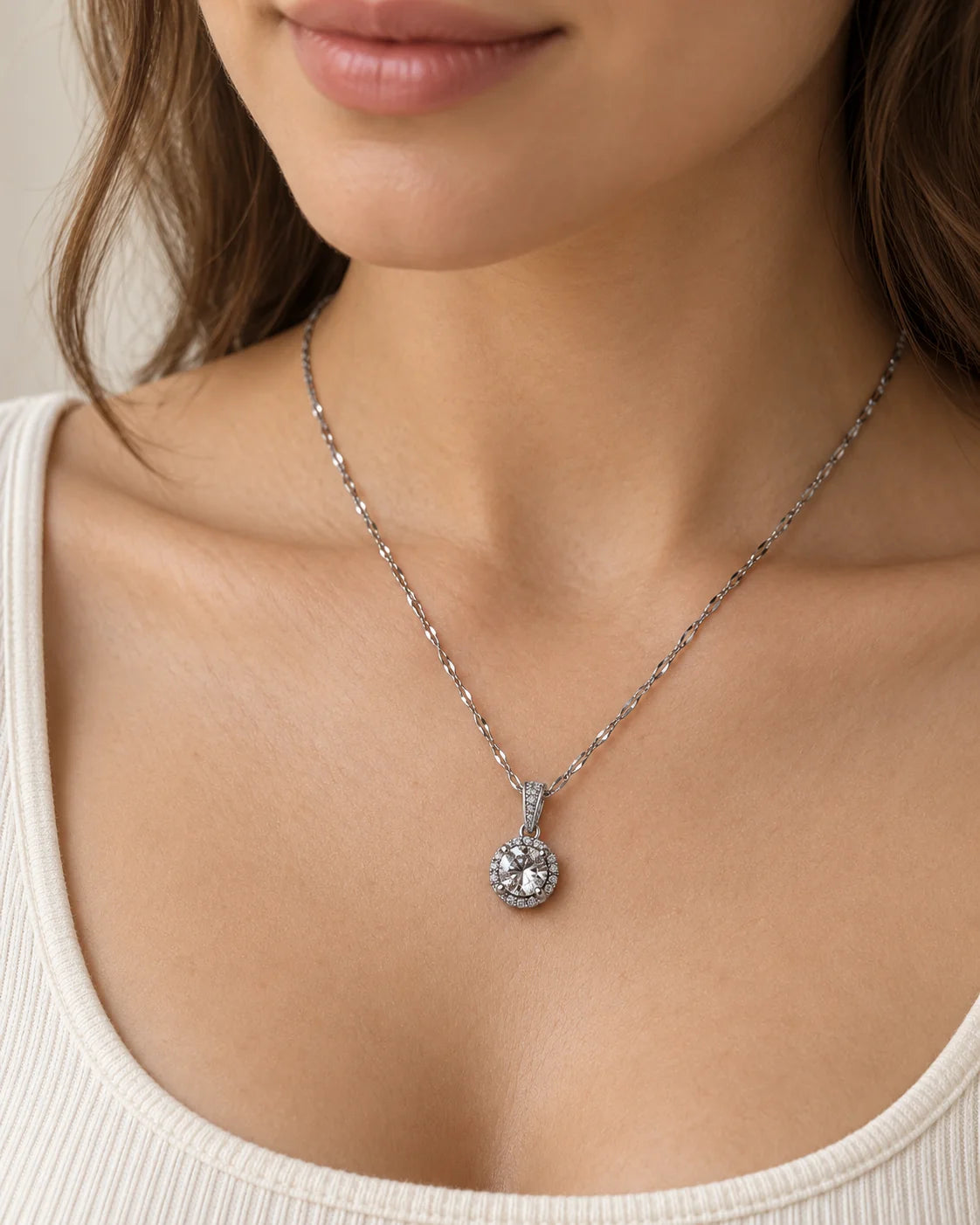 Model wearing the Luna silver round halo pendant necklace with an ivory scoop-neck top