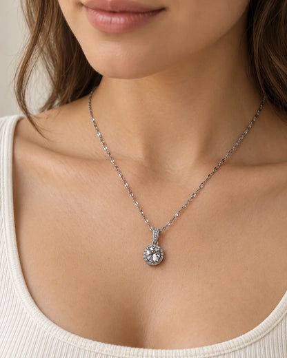Model wearing the Luna silver round halo pendant necklace with an ivory scoop-neck top