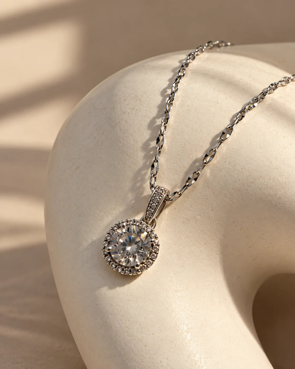 Luna silver halo necklace draped over a sculptural ivory plinth