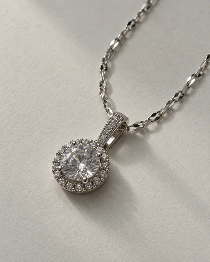 Luna silver round halo pendant on a faceted link chain against soft grey