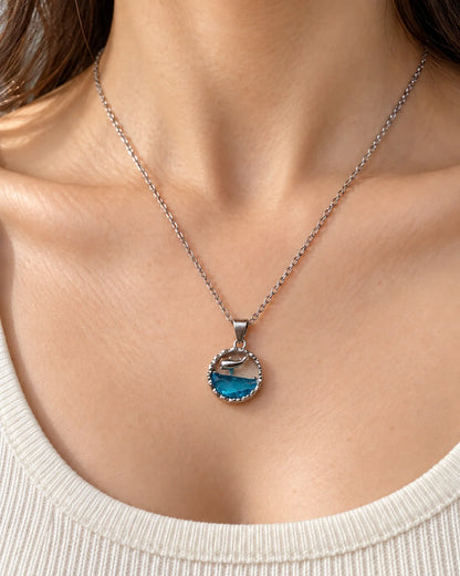 Model wearing the Delphine ocean blue dolphin pendant necklace at the collarbone