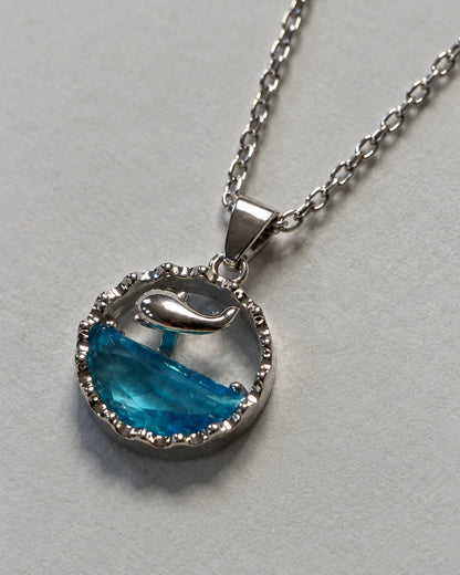 Delphine silver dolphin pendant with ocean-blue inlay against soft grey